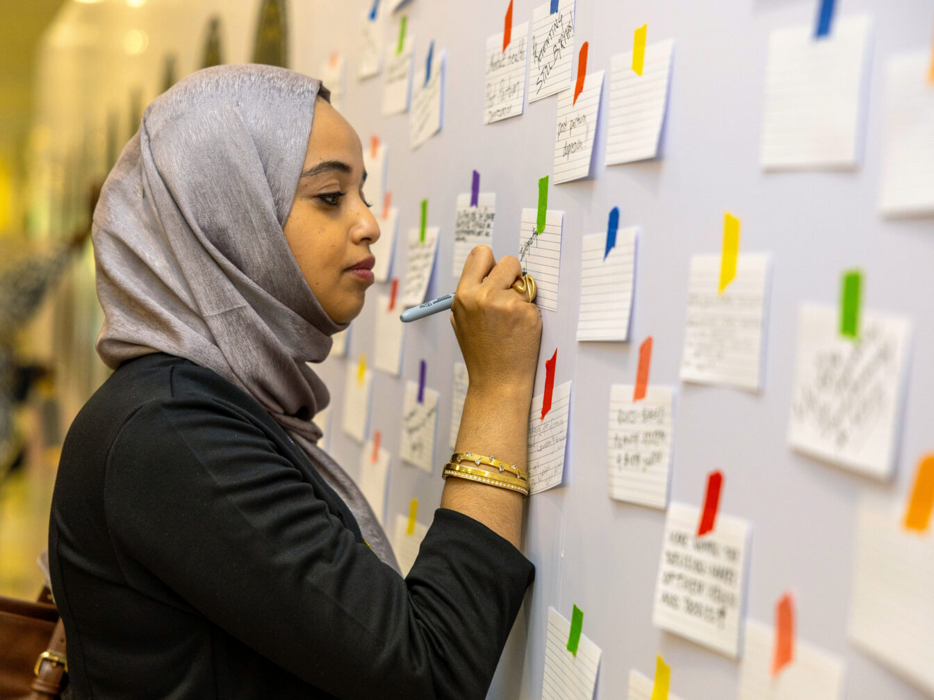 A woman writes on a note on the wall at International Maternal and Newborn Health Conference 2026