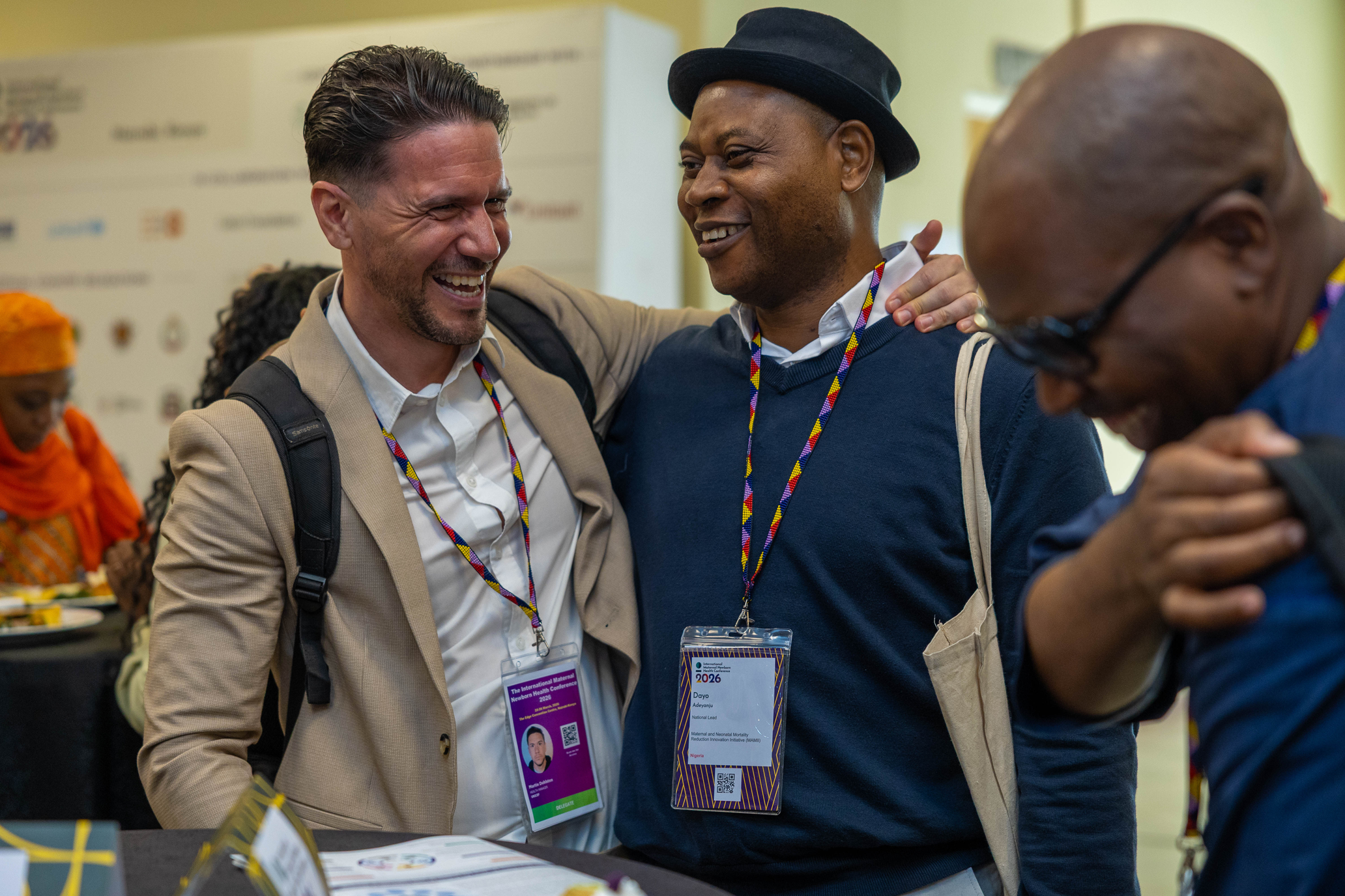 Three conference attendees laugh together at the International Maternal and Newborn Health Conference in 2026