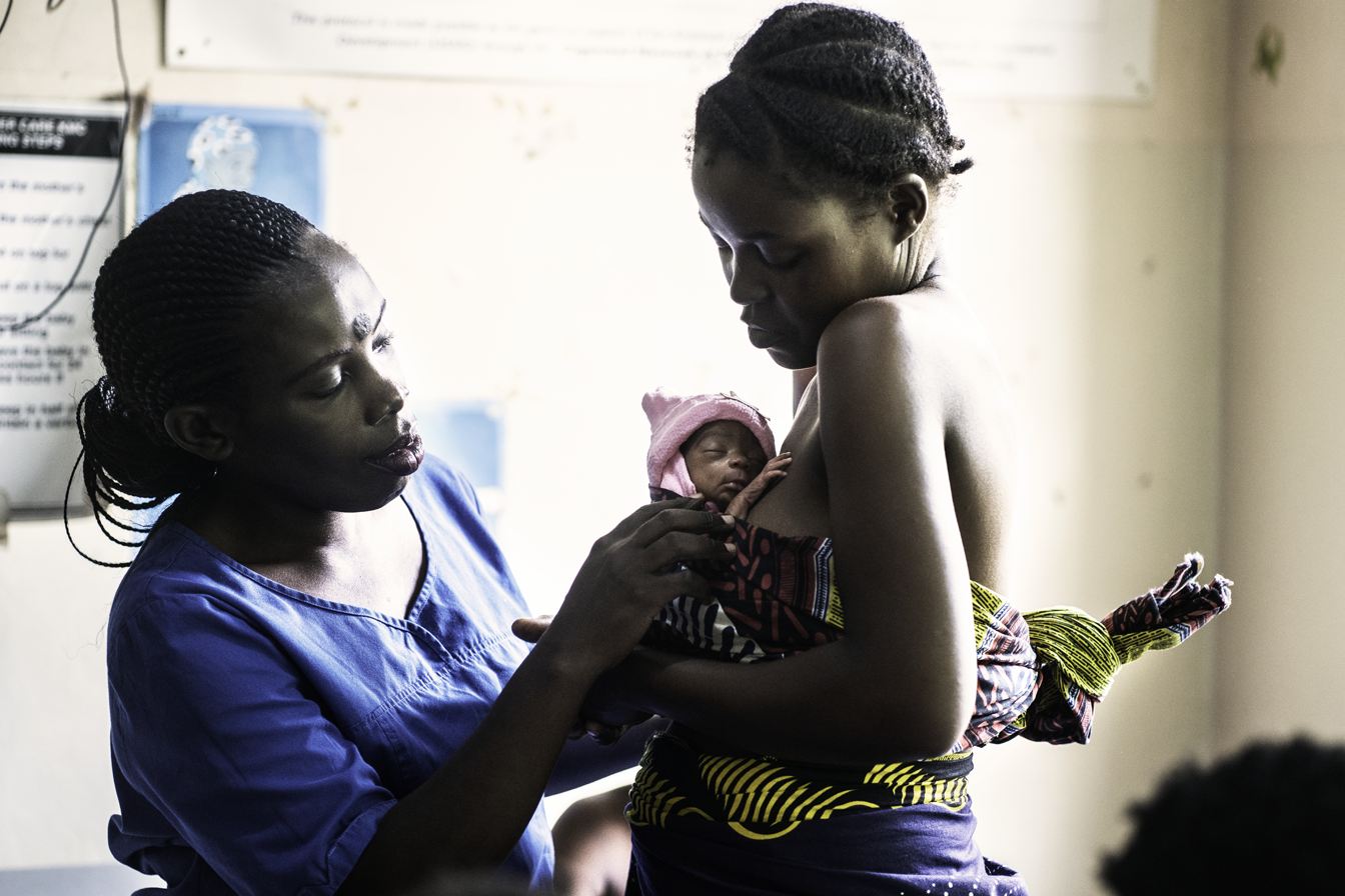 A nurse helps a woman with her baby in a medical setting in Malawi