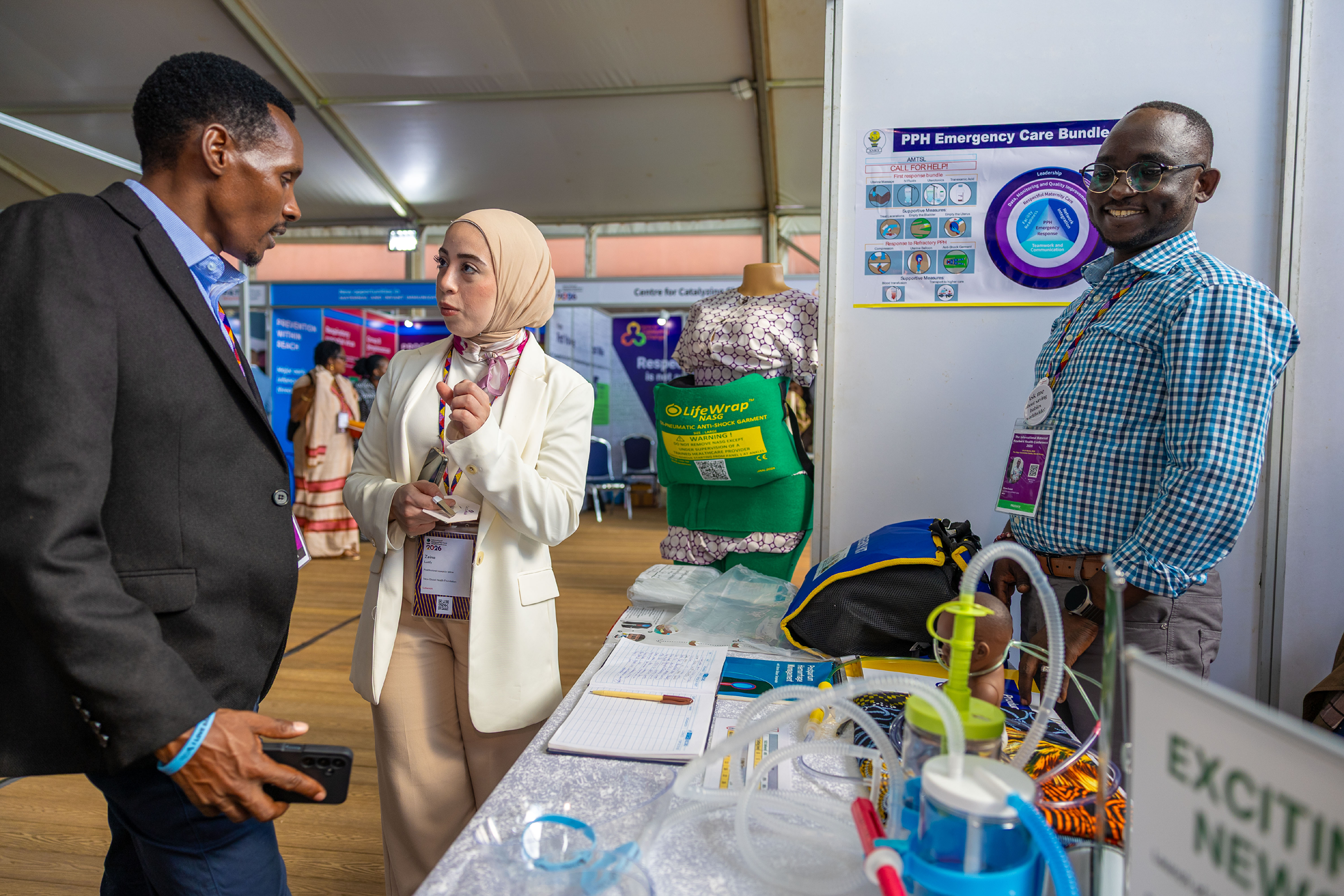 Three attendees stand at a booth in the exhibit hall at the International Maternal and Newborn Health Conference 2026